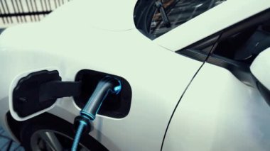 Akıllı telefon akü durumu arayüzünü elinde tutan iş kadını akıllı EV mobil uygulama ile otomobil parkındaki şarj istasyonundan elektrik şarj eden çevre dostu EV araba. İnceleyin