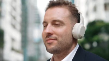 İş adamlarının kulaklıklarını kapat ve neşeli ve motive edici bir şekilde müzik eşliğinde dans et. Yetenekli proje yöneticisi şehir merkezinde bulanık arkaplanlı rahat şarkılar dinlemeyi sever. Urbane.