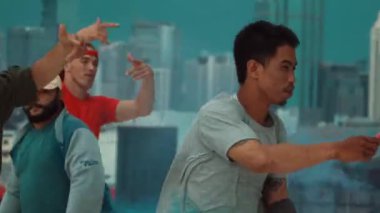 Bir grup çok kültürlü hippi çatıda işaret fişeği çalıyor. Zenci dumanı tutan çekici bir sokak dansçısı hip-hop müzik eşliğinde break dans yapıyor. Açık hava sporu 2024. Sokak dansı. hiphop.