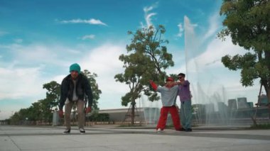 Profesyonel çekici hipster, Fountain ile sokak dansı yapıyor. Yakışıklı bir adamın B-boy ayak egzersizi sahnesi. Mavi arka plan. Modern yaşam tarzı. Açık hava sporu 2024. Yumuşak bir şekilde..