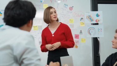 Genç ve güzel profesyonel iş kadını, yaratıcı iş toplantısında yakışıklı yönetici dinlerken zihin haritalama ve istatistiksel grafik kullanarak pazarlama fikrini kendine güvenle sunuyor. Tertemiz..