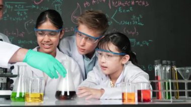 BTMM sınıfında kimya teorisi üzerine karatahta deney yaparken deney yapan bir kız. Karışık ırkları olan bir grup lise öğrencisi ve öğretmen birlikte bilimsel aktivite yapıyorlar. Öğretim