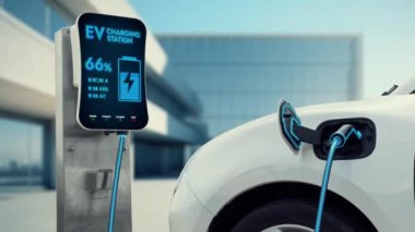 Modern ve fütüristik bina arka planında akıllı EV şarj istasyonundan elektrikli araba şarj oluyor. Alternatif ve sürdürülebilir enerji kullanan şarj edilebilir EV arabaların teknolojik gelişimi. İnceleyin