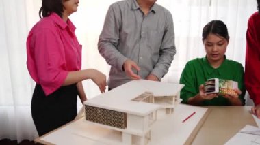 Mimari ekipman kullanarak yavaş çekim ev tasarımcısı bir plan çizerken, iç mimari tasarımcı da müşterilerin talebine göre renk örneklerinden uygun renkler seçiyor. Değiştirilmiş