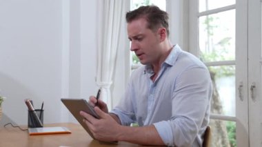 İş adamı, evde dizüstü bilgisayarla iş problemini çözmeye çalışıyor, evde masasında oturmuş, stresli ve hayal kırıklığına uğramış bir ifadeyle probleme çözüm bulmaya çalışıyor. Titiz