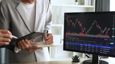 Menkul kıymetler borsası pazarlamasını inceleyen borsa yatırımcıları, zarar ve kazanç için mum bar fiyatlarını analiz eden monitörlere bakıyor. Filizlenen