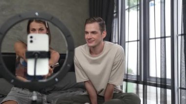 Sosyal medya için güzellik ve kozmetik video içeriği hazırlayan genç bir kadın erkek arkadaşını model ve ışık yüzüğü olarak kullanıyor. Güzellik blogcusu seyirciye ya da takipçiye güzellik bakımını gösteriyor. Düzenle