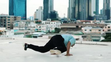 Profesyonel beyaz dansçı, şehir ya da şehirle çatıda sokak dansı yapıyor. Genç adamın sokak dansı yaparken dondurucu poz vermesi. Açık hava sporu 2024 hiphop..