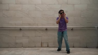 Yakışıklı hippi dans ederken müzik dinler ya da dans ederken dans eder. Çekici bir sokak dansçısı B-boy ayak sesleri çıkarıyor. Serbest dans konsepti. Yaşam tarzı. Açık hava sporu 2024. Yumuşak bir şekilde..