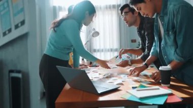 Dizüstü bilgisayara bakan ve logo tasarımını işaret eden yetenekli bir iş ekibi ana tema rengini seçme ve pazarlama kampanyasını planlama kararı alıyor. Birlikte çalışan akıllı bir grup. Sempozyum.