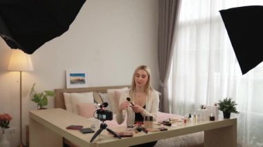 Sosyal medya için güzellik ve kozmetik video içeriği hazırlayan genç bir kadın. Güzellik blogcusu kameraya gülümserken seyircilere ve takipçilere güzellik bakımını gösteriyor. Blithe