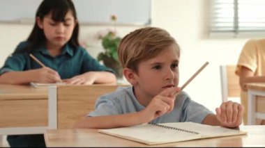 Kafkas çocuk karatahtaya bakarken çeşitli yetenekli öğrenciler okulda öğreniyor ve not alıyor. Çocuklar test yaparken karatahtanın önünde günlük kıyafetlerle oturan zeki çocuk. Pedagoji.