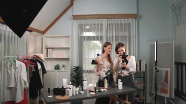 Etkilenen iki ortak canlı yayında video görüntülerini çekiyor makyaj malzemesi prim sosyal medya veya blog. Kozmetik stüdyosu ışıklandırmalı mutlu genç kız çevrimiçi pazarlama oturumu yayını için..