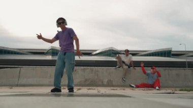 Bir grup Asyalı break dansçı, çok kültürlü arkadaş desteği ve hareketli hip hop müziğiyle sokak dansı yaptılar. Çekici yakışıklı hippi sokak dansında break dansçı. Açık hava sporu 2024. Yumuşak bir şekilde..