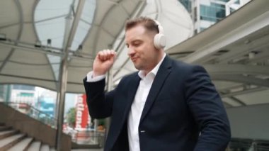 Mutlu iş adamı kulaklık takıyor, müzik dinliyor ve şehir merkezinde canlı bir şekilde yürürken müzik eşliğinde hareket ediyor. Menajer kulaklık takar ve gevşetici kafiyelerin keyfini çıkarır. Urbane.