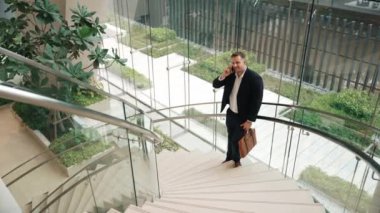 Kafkas işadamı akıllı telefon kullanarak müdürü arıyor ve mali raporları tartışıyor. Erkek lider, modern binada merdivenlerde dururken telefonla pazarlama ekibini konuşuyor. Urbane.