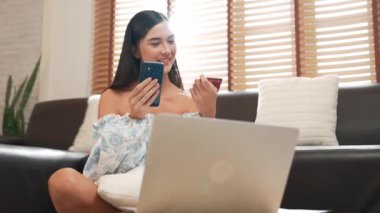 Genç bir kadın internet bankacılığı için kredi kartıyla dizüstü bilgisayar kullanıyor. Evinde online ödeme kapısı ile E ticareti yapıyor. Banka kartıyla modern ve kullanışlı online satın alma. Blithe