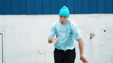 Caddede hareketli bir şekilde dolaşan genç hipster 'ın yakın çekimi. Kafkasyalı break dans koreografı hip hop tarzında dans ediyor. Enerjik dansçı B-boy dansı yapıyor. Açık hava sporu 2024 hiphop..