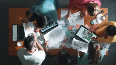 Planı elinde tutan inşaat mühendisi ekibinin en iyi görüntüsü ve dizüstü bilgisayar, proje planı ve planıyla masada duruyor. Yapışkan notları planlayan ve yazan yetenekli proje yöneticisinin havadan görünüşü. Sempozyum.