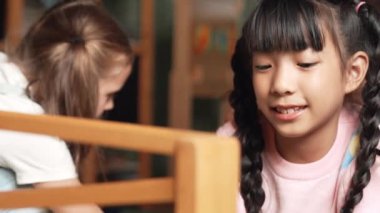 Arkadaşlarıyla oyun odasında oynaşan Asyalı tatlı bir kızın yakın çekimi. Çeşitli çocuklar hayal gücünü geliştirmek için araba modeli kullanıyorlar. Sevimli çocuklar robotik modelcilik oynamaktan hoşlanırlar. Eğitici bir oyun. Etkinlik.