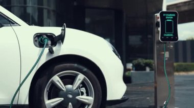 İş adamı, şehir merkezindeki şarj istasyonundan ya da otoparktan EV şarj aletini çıkardı. Şehir yaşam tarzında alternatif temiz enerji kullanan çevre dostu şarj edilebilir araba. İnceleyin.