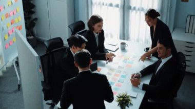 İş adamlarının üst görüşü pazarlama stratejisini açıklıyor ve renkli yapışkan notlar kullanarak fikri seçiyor. Profesyonel pazarlama ekibi toplantı odasında beyin fırtınası yapıyor ve finansal planlar yapıyor. Müdürlük.