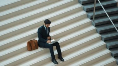 Merdivenlerde dizüstü bilgisayar kullanarak yatırımcıların çalışma ya da planlama stratejisinin en üst görüntüsü. Modern bir otelde dizüstü bilgisayar kullanarak veri analizi yapan takım elbiseli profesyonel bir iş adamı. Sevinçli..