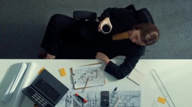 Üst düzey inşaat mühendisi yapışkan notlar yazıyor ve dizüstü bilgisayara bakıyor. Hava görüntüleme mimarı bilgisayar analizi yaparken toplantı masasında oturuyor ve bina yapısını hesaplıyor. Hizalama.