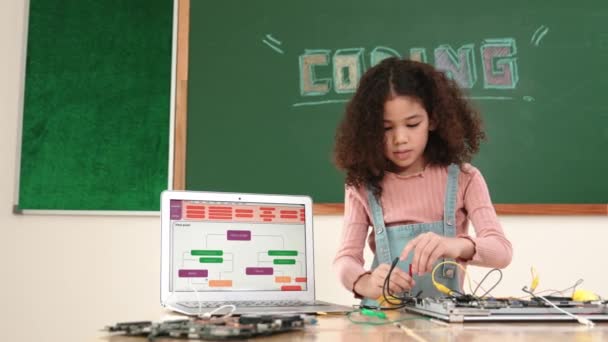똑똑한 소녀는 철사를 사용하여 검열하고 고치는 기계를 고치고 까만판의 노트북 — 비디오