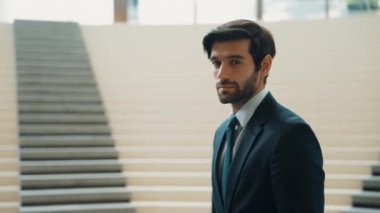 İş adamı kameraya bakarken kollarını kavuşturup arkasını dönüyor. Zeki, yakışıklı proje yöneticisi kameraya poz verirken kendine güvenen, arka planı bulanık bir şekilde merdivenlerde gülümsüyor. Sevinçli..