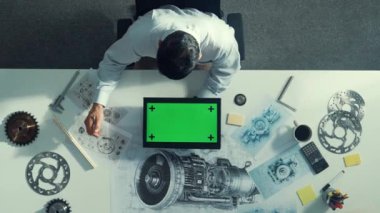 Türbin motor çizim tasarımı, metal teçhizat ve mimari ekipmanlar etrafa saçılmış yeşil ekranı incelerken kağıt üzerine yazı yazan yetenekli mühendisin üst görünümü. Hizalama.