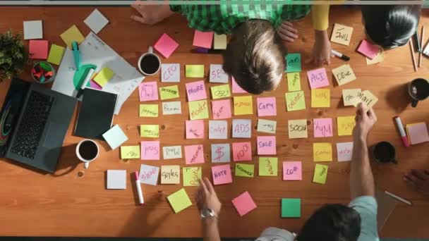 熟練したビジネスの人々のトップビューは スティッキーノートでアイデアを書いたり ホワイトボードに固執しながら会議室で計画を議論します 戦略を立案するために協力する多様なチームのグループ コンベンション — ストック動画