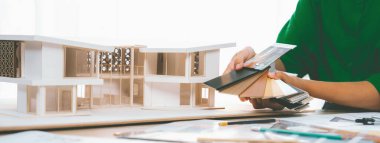 Yetenekli iç mimarın kırpılmış bir görüntüsü, renk örnekleriyle karşılaştırarak ev modeli için uygun zemin malzemesi seçer. Yaratıcı çalışma ve tasarım konsepti. Değiştirilmiş.