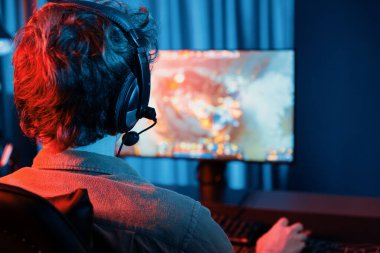 Savaş arenasında çoklu oyunlar takımıyla Moba 'da savaşan genç oyun flamasının sunucu kanalı, neon dijital ışık modern odasındaki arka görüntü ile bilgisayar monitöründe kulaklık takıyor. Toplayıcı.