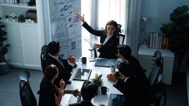 Akıllı yönetici projesinin üst görünümü beyaz tahtaya zihin haritası ve finansal grafik ile işaret ediyor ve çeşitli yatırımcılar hisse yatırım grafiğini dinleyip analiz ederken pazarlama fikrini açıklıyor. Müdürlük.