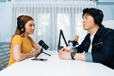 Gülümseyen radyo etkili sunucusu kulaklık takıyor kadın konuşmacı ile röportaj yapıyor sosyal medya internet sitesinden dinleyicilere bilgi paylaşıyor stüdyo kaydında sabah canlı yayın kanalı. İnfobahn.