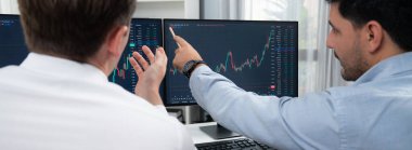 Borsa simsarları panorama manzarasında iki ekranla karşılaştırma yaparak, monitörde analiz yaparak borsa borsasını tartışıyorlar. İş yerindeki finansal teknoloji krizi kavramı. Satılabilir.