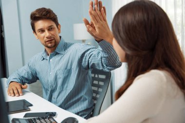 Gülümseyen mutlu iş arkadaşları beşlik çakıyor aynı zamanda yaratıcı proje planını yumrukluyor ve sabahları modern ofiste gündelik işlerde en yüksek kârı elde ediyorlar. Varsayım.