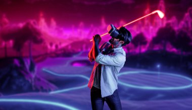 Sanal dünyaya girmek için sanal gözlük takan beyaz bir adam metaevrende golf oynuyor. Sanal gerçeklik gözlüğü kullanan yakışıklı oyuncu neon golf sahasına giriyor. Yenilik. Spor. Sapma.