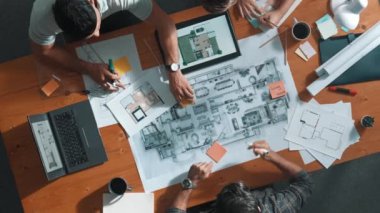 Bina planına bakarken inşaat mühendisinin elindeki belgelerin en alttaki görüntüsü. Mimarlık takımının fikir üretme ve planlama alanındaki hava görüşü masada planlı otururken. Sempozyum.