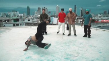 İspanyol hipster dansları şehrin mavi gökyüzü manzaralı çok kültürlü arkadaşlarıyla çevrili. Çatıda bir grup sokak dansçısı sahne alıyor. Aktif, eğlenceli, mutlu atmosfer. Açık hava sporu 2024 hiphop..