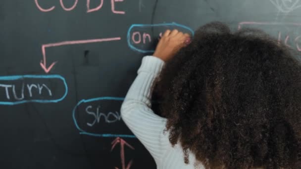 ハッピーアフリカの少女はブラックボードを書き エンジニアリングプロンプトやコーディング Stemテクノロジークラスルームで書かれたプログラミングシステムでボード上に立っている間 カメラで振動するように回転します エラー — ストック動画