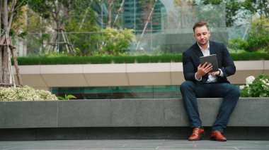 Profesyonel işadamı, pazarlama ekibinin raporlarını okuyarak tablet üzerinde çalışırken parkta oturuyor. Mutlu yönetici artan satışlar ya da Eko City 'de gülümserken başarılı bir proje arıyor. Urbane
