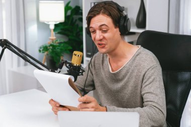 Akıllı yayıncının sunucu kanalı canlı sosyal medya yayını ile dinleyicilere senaryo okuyarak, kulaklık takarak modern ev stüdyosundaki video flamalarını kaydediyor. Bireysel.