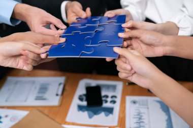 Çok ırklı iş adamları yapboz parçalarını tutuyor ve onları etkili çözüm çözümleri olarak birleştiriyor takım çalışması, ortak görüş ve çeşitli yetenekleri birleştiren ortak hedef. Çok titiz.