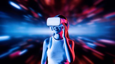 Zeki bir kadın, metaevreni birbirine bağlayan VR kulaklık takan neon ışıklarla çevrili duruyor. Gelecekteki siber uzay topluluğu teknolojisi. Uzaklara bakan zarif bir kadın ve tatmin edici bir şekilde gülümsüyor. Halüsinasyon.