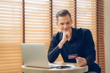 Genç adam internet bankacılığı için kredi kartlı dizüstü bilgisayar kullanıyor. İnternet üzerinden alışveriş yapıyor. Banka kartıyla modern ve kullanışlı online satın alma. Açılıyor