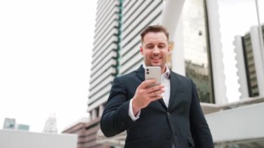 Kafkasyalı iş adamı şehir merkezinde dururken cep telefonlarını kontrol ediyor ve pazarlama ekibinden satış raporlarını inceliyor. Yetenekli bir yönetici cep telefonu üzerinde çalışıyor ve veri analizine bakıyor. Urbane.