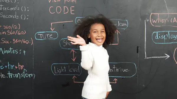 快乐的非洲女孩写黑板 转身对着相机挥手 而站在船上的工程提示或编码 编程系统写在Stem技术教室 Erudition — 图库照片