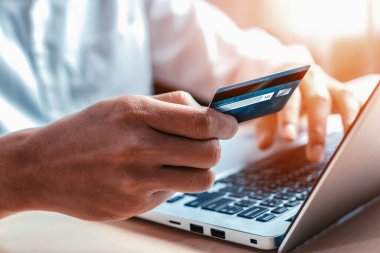 Genç adam, laptop bilgisayar başvurusu ya da web sitesinde online alışveriş yapmak için kredi kartı kullanıyor. E-ticaret ve online alışveriş konsepti. uds